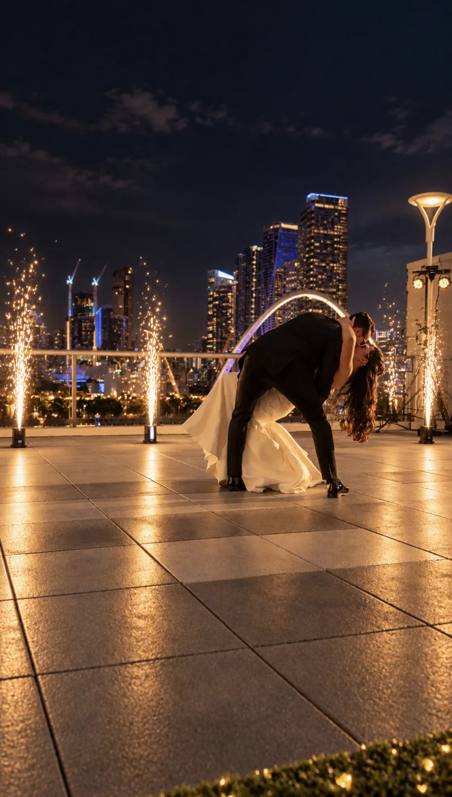 Couple kissing on a rooftop between cold spark fountains, with the Miami skyline behind