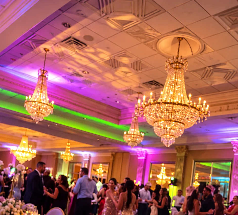 Guests dancing under chandeliers in pink and green lighting